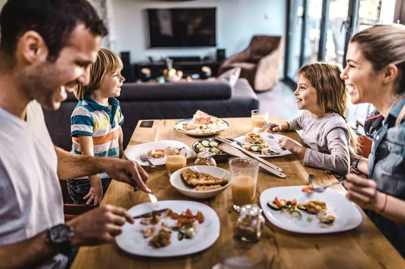 Happy family communicating during lunch time in dining room. Focus is on kids.