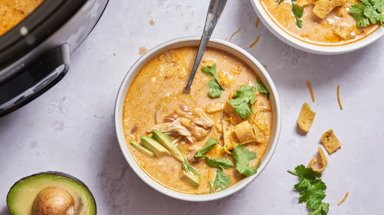 bowl of enchilada soup with cilantro, chips, avocado