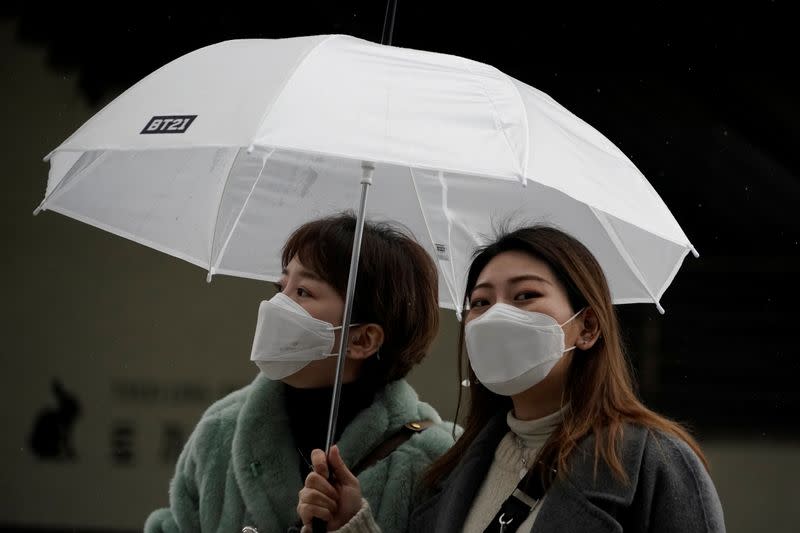 Passengers wearing masks to prevent contacting the coronavirus walk outside Seoul Railway Station in Seoul