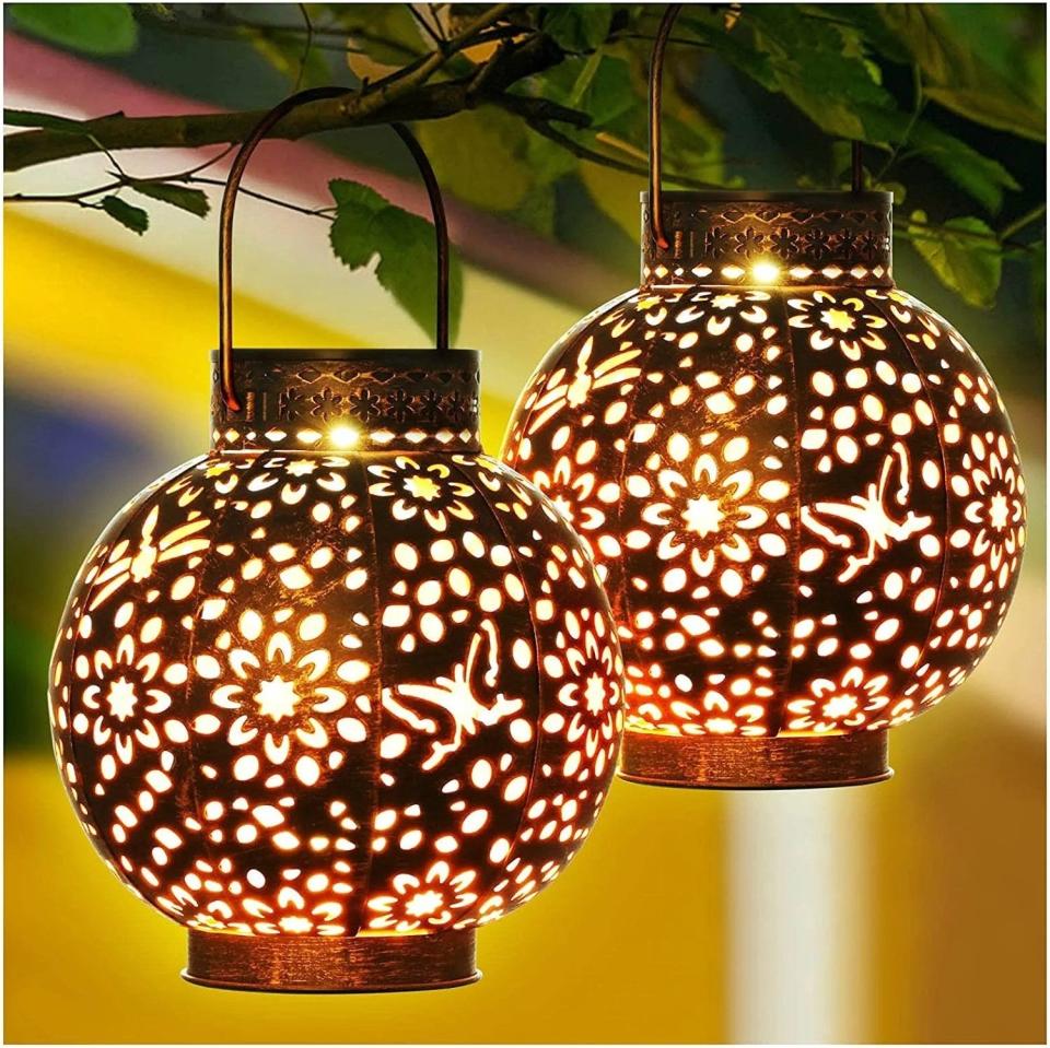 the solar lanterns with an intricate pattern hanging from a tree