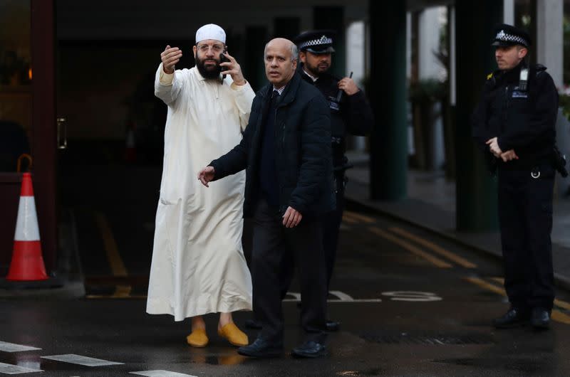 A man gestures as Police officers are seen outside the London Central Mosque in London