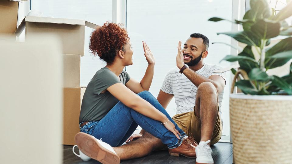 Shot of a young couple giving each other a high five while moving house.