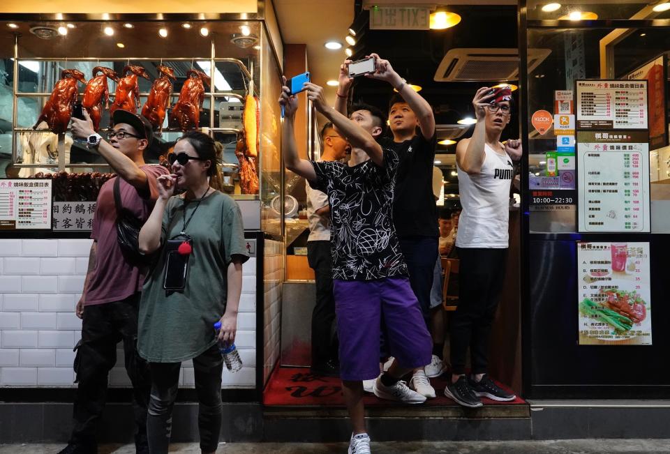 People at a restaurant take pictures of police water cannons in Hong Kong, Sunday, Sept. 29, 2019. Protesters and police clashed in Hong Kong for a second straight day on Sunday, throwing the city's business and shopping belt into chaos and sparking fears of more ugly scenes leading up to China's National Day this week.(AP Photo/Vincent Yu)