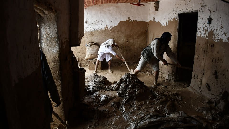 Afghan men shovel mud from a house following flash floods. - Atif Aryan/AFP/Getty Images