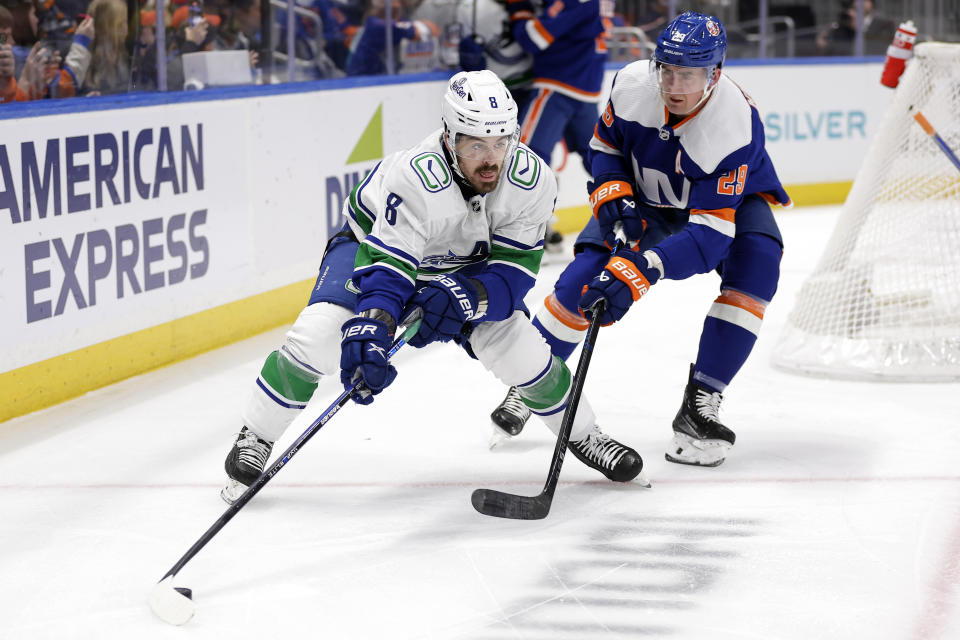 Vancouver Canucks right wing Conor Garland (8) controls the puck in front of New York Islanders center Brock Nelson in the first period of an NHL hockey game Tuesday, Jan. 9, 2024, in Elmont, N.Y. (AP Photo/Adam Hunger)