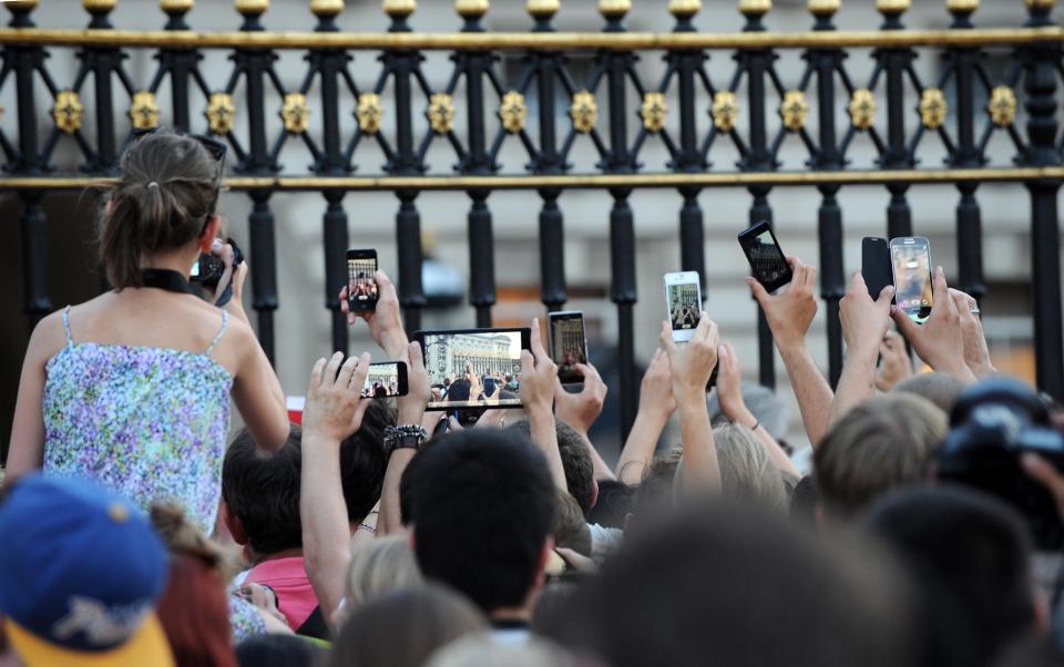 Members of the public try to take photos of an easel in the Forecourt of Buckingham Palace with the notification, to announce the birth of a baby boy, at 4.24pm to the Duke and Duchess of Cambridge at St Mary's Hospital in west London.