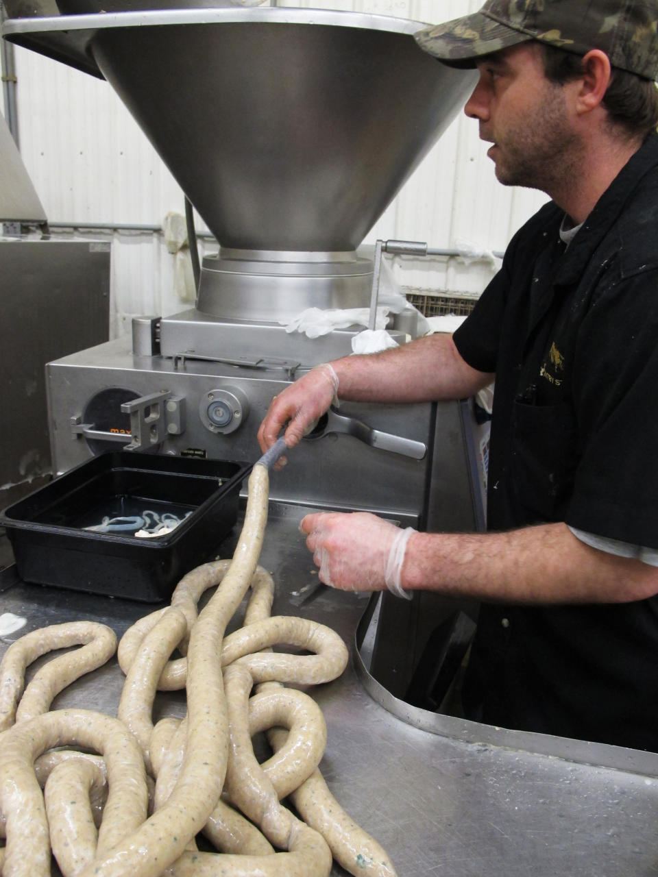 In this Wednesday, April 10, 2013 photo, processing department manager Chris Cote at the Country Store market handles boudin as it comes out of sausage making machine in Pennsdale, Pa. The sausage is popular in Louisiana. An influx of workers from the South to fill jobs in the natural gas industry in north-central Pennsylvania has led area catering businesses, restaurants and grocery stores to offer more Southern cuisine like jambalaya and boudin. (AP Photo/Genaro C. Armas)