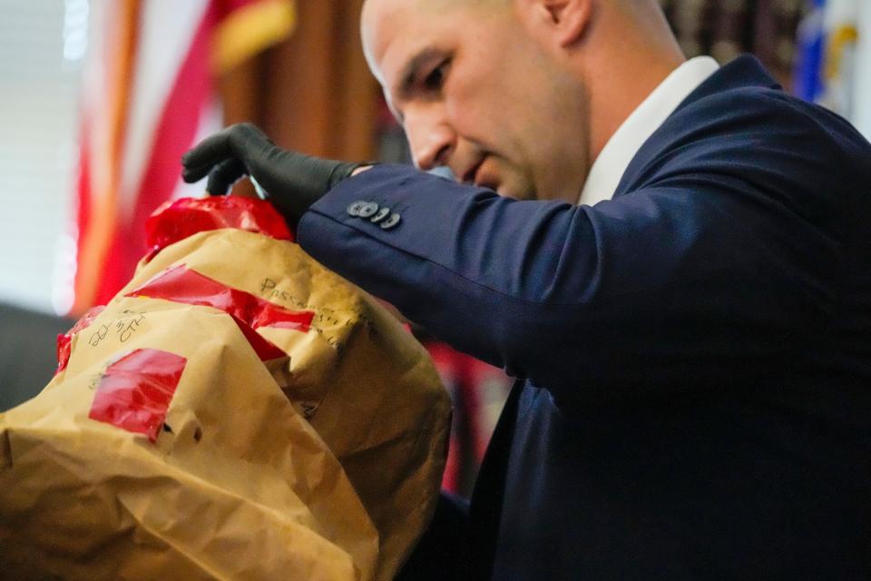 Massachusetts State Police Trooper Michael Proctor opens an evidence box to show the jury a broken tail light while testifying, Monday, June 10, 2024, at Norfolk Superior Court, in Dedham, Mass., during the trial for Karen Read. Read is accused of killing her boyfriend, Boston police Officer John O'Keefe, in 2022. (Kayla Bartkowski/The Boston Globe via AP, Pool)