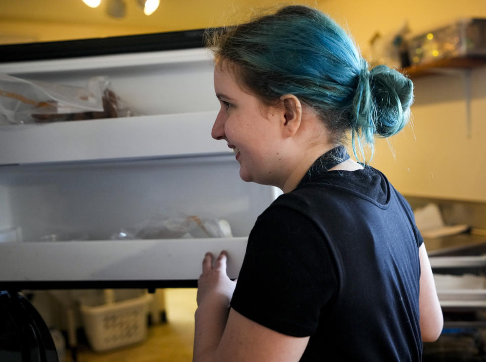 Khloe Warne, 12, looks for an ingredient in a freezer at the family bakery Beef Cakes, Thursday, May 18, 2023, in Grants Pass, Ore. Khloe was put on shortened school days by her school district after incidents in which she fought with students and threw a desk in outbursts her mother, Alyssa, attributes to a failure to support her needs. Now she only attends school one day a week for two hours, and hasn't been on a regular school schedule for years, instead spending much of her time at her mother's bakery or at the local library. (AP Photo/Lindsey Wasson)