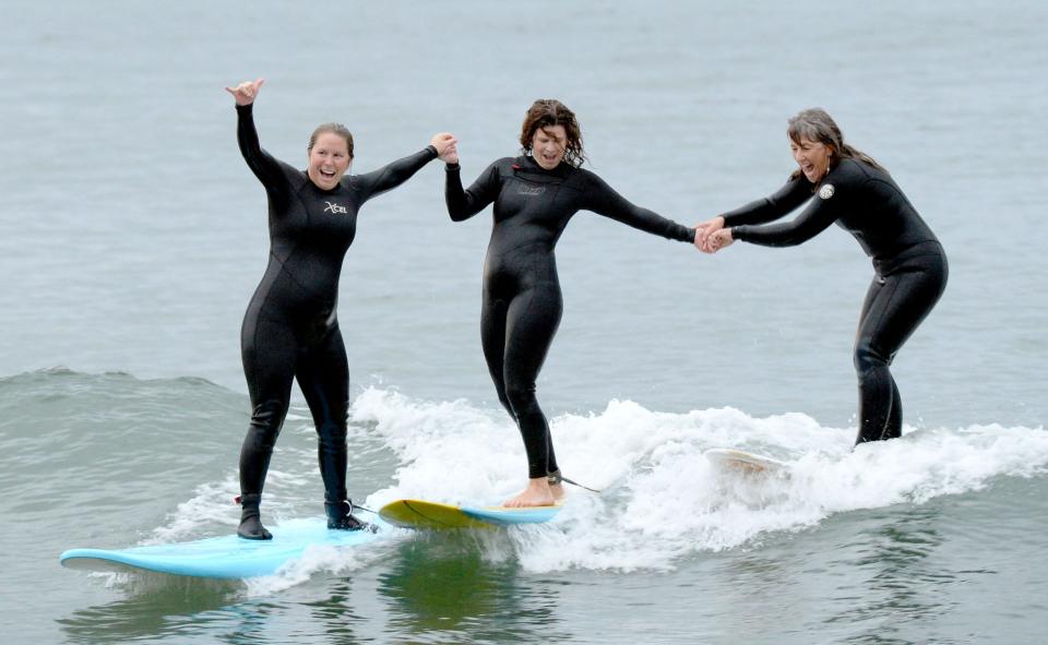 Kate Logsdon, left, Keri Nesbitt and Kim "Flow" Hansmeier, all of Ventura, hold hands while surfing at Mondos Beach on Thursday, Dec. 1, 2022. The women gather regularly in what they call a surfing sisterhood inspired in part by local surf pioneer Mary Monks.