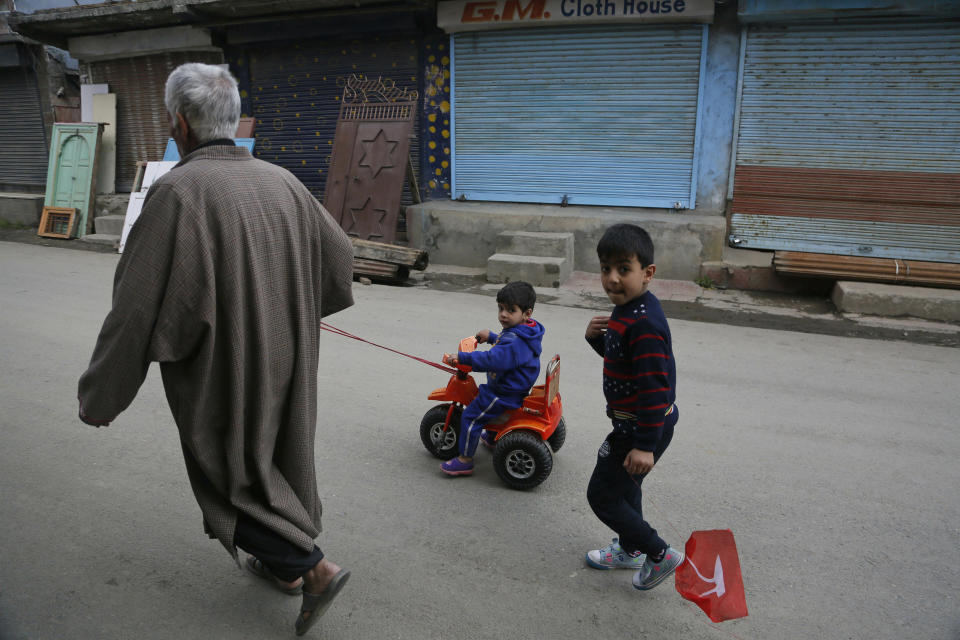 An elderly Kashmiri man pulls a child on a tricycle during a strike called on the second phase of India's general elections, in Srinagar, Indian controlled Kashmir, Thursday, April 18, 2019. Kashmiri separatist leaders who challenge India's sovereignty over the disputed region have called for a boycott of the vote. Most polling stations in Srinagar and Budgam areas of Kashmir looked deserted in the morning with more armed police, paramilitary soldiers and election staff present than voters. (AP Photo/Mukhtar Khan)