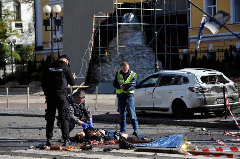 Expertos de la policía examinan un cuerpo en el centro de la capital ucraniana de Kiev después de un ataque con misiles el 10 de octubre de 2022. 