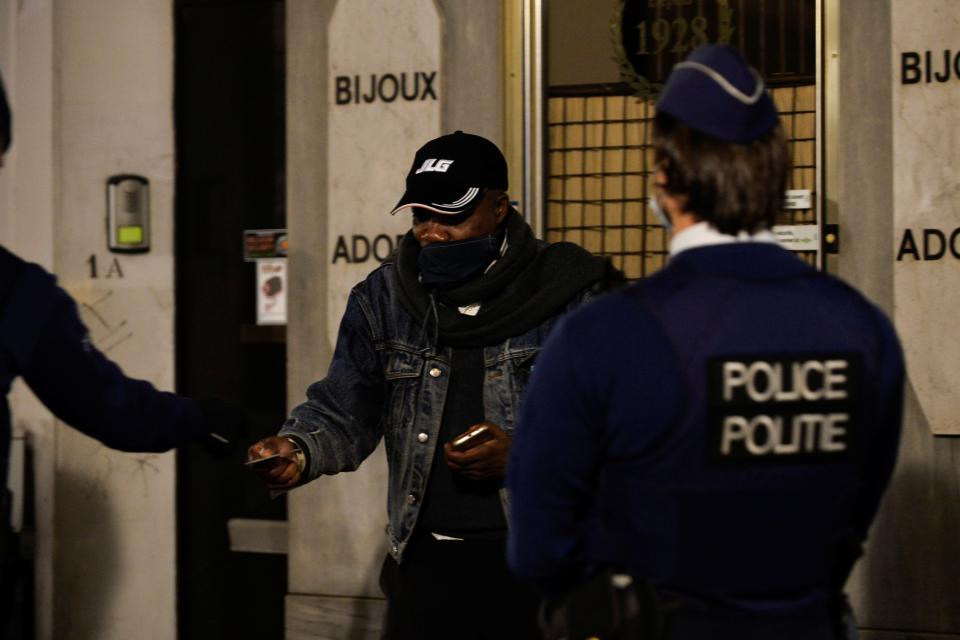 Police officers check the documents of a man while patrolling in central Brussels during a curfew imposed by the Belgian government (REUTERS)