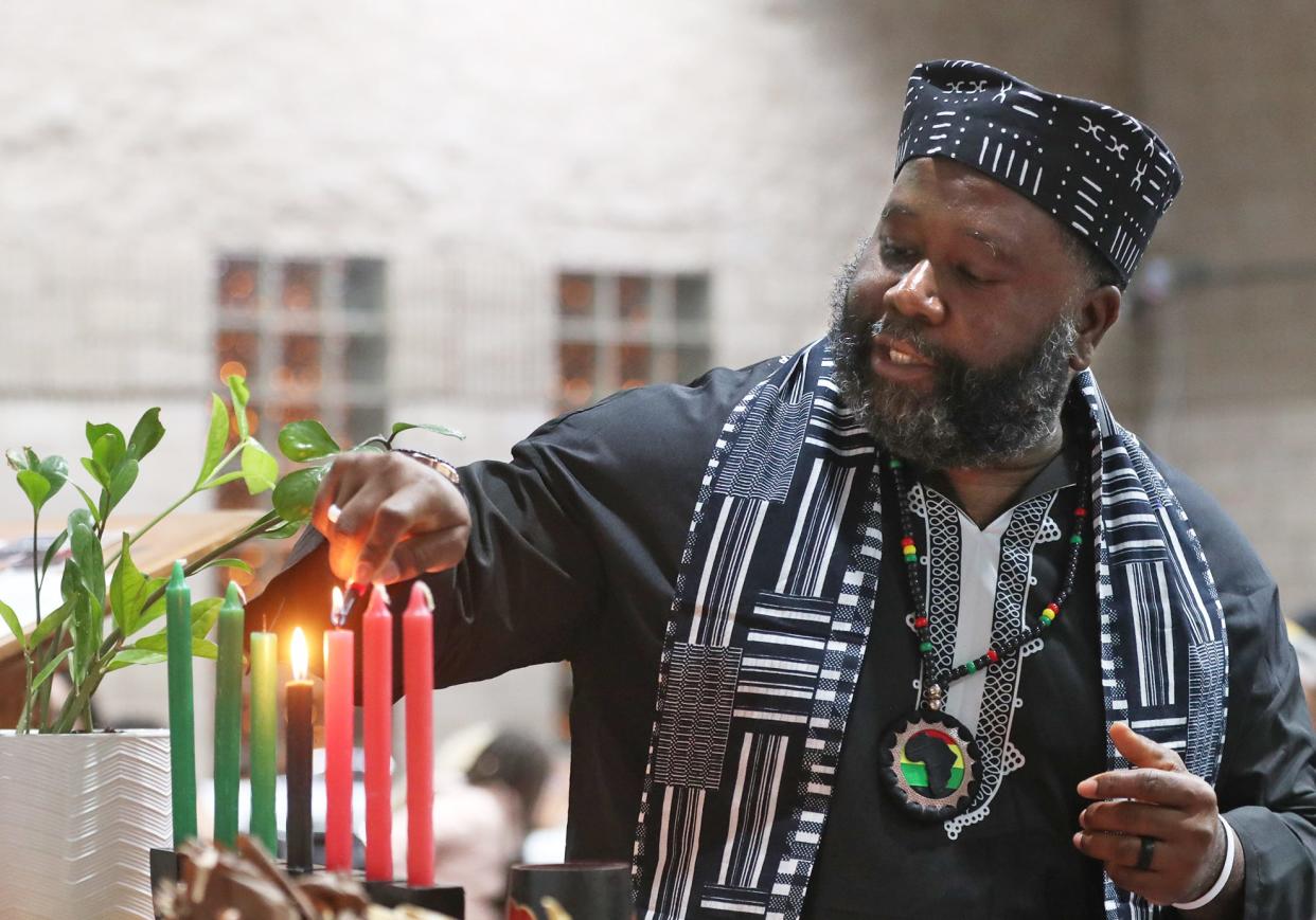 Kwa Hill of Akron lights a third candle for Ujima, the principle celebrated on the third day of Kwanzaa signifying collective work and responsibility, at the Gus Johnson Community Center in Akron on Thursday. Kwanzaa is seven-day celebration of African-American culture from Dec. 26 to Jan. 1.