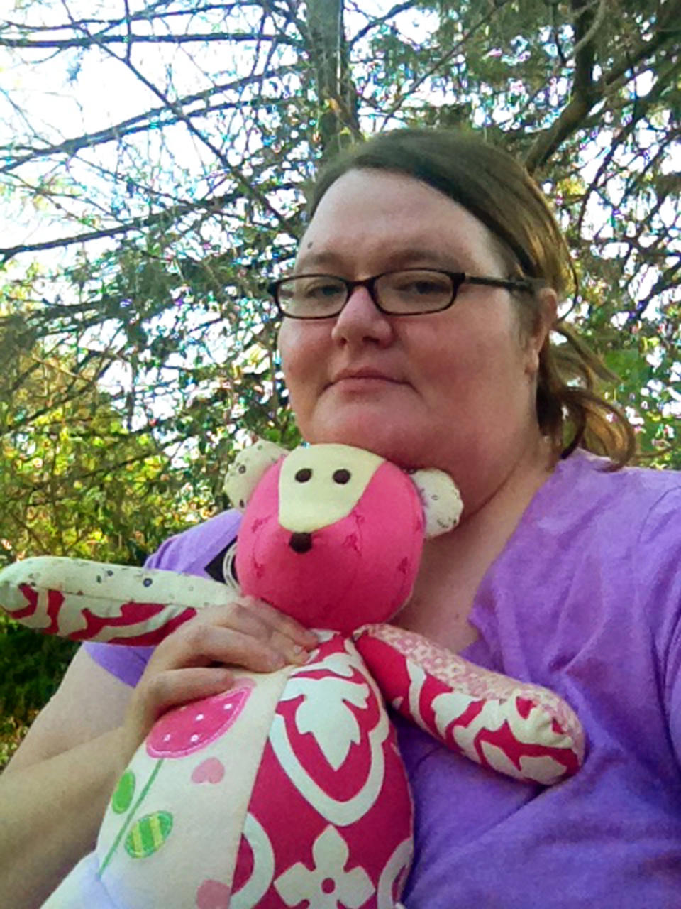 This April 2014 photo released by Kristine McCormick shows her posing in Indianapolis with a memorial teddy bear in honor of her daughter Cora, who died when she was five days old from an undetected congenital heart defect as she fed at her mother's breast on Dec. 6, 2009. (AP Photo/Kristine McCormick)