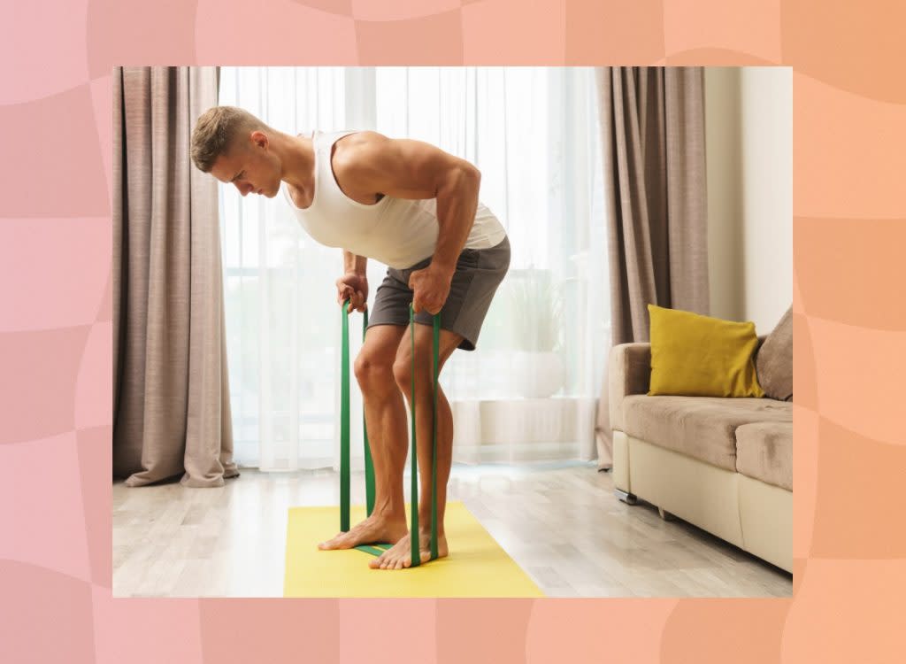 fit, muscular man doing resistance band row exercise in bright living room