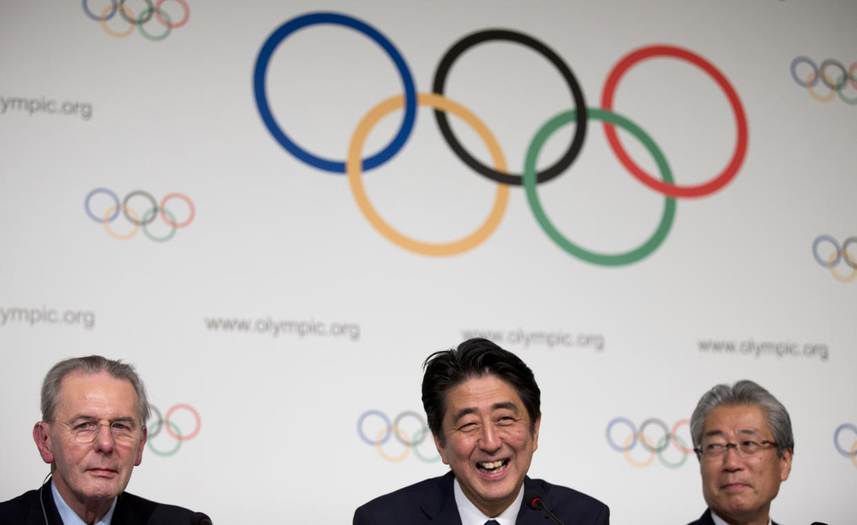 FILE - Then Japan's Prime Minister Shinzo Abe, center, smiles next to the President of the International Olympic Committee Jacques Rogge, left, as Tokyo 2020 Olympic Bid Committee President Tsunekazu Takeda, right, looks on after signing the Host City Contract for the 2020 Olympic Games in Buenos Aires, Argentina, Saturday, Sept. 7, 2013. Former Prime Minister Shinzo Abe was the country’s central figure in landing the 2020 Olympics for Tokyo. Abe died after being shot while campaigning in western Japan on July 8, 2022. (AP Photo/Natacha Pisarenko, File)