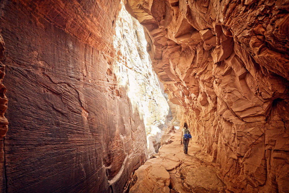 A lone female hiker walking through a slot canyon.