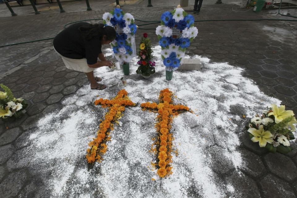 In this Oct. 21, 2015 file photo a woman creates a makeshift memorial, in front of the Municipal Palace in Ajalpan, Puebla, Mexico, for two pollsters mistaken for criminals who were killed and burned by a mob.  / Credit: Marco Ugarte / AP