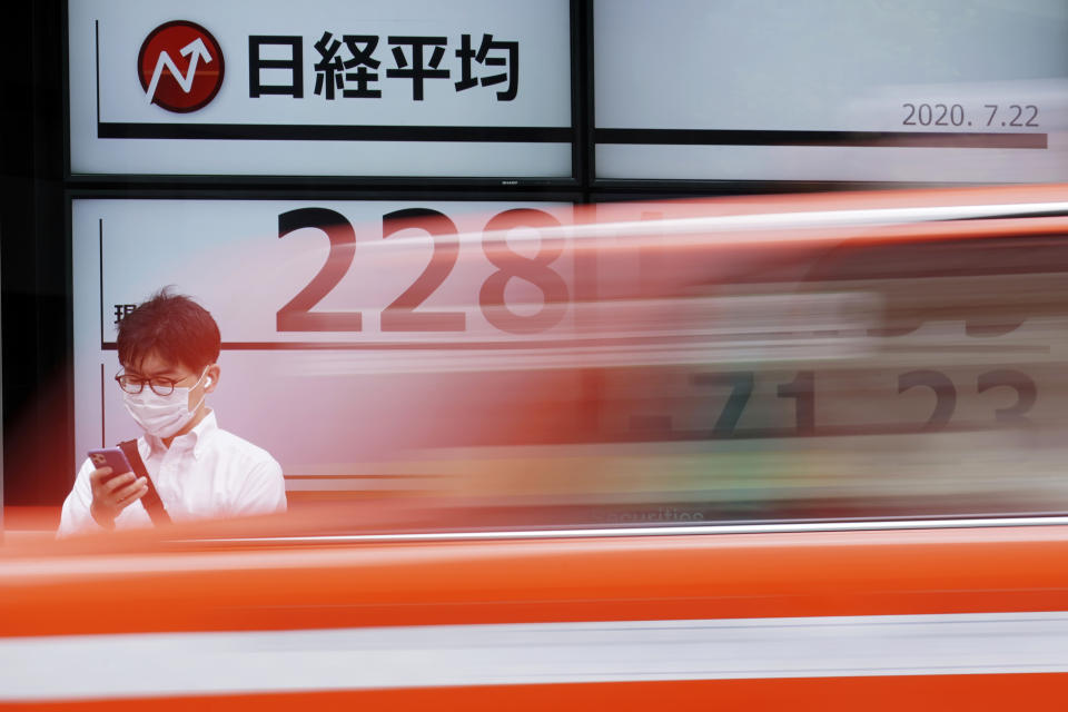 A man wearing a face mask stands near an electronic stock board showing Japan's Nikkei 225 index at a securities firm as a taxi passes by in Tokyo Wednesday, July 22, 2020. Shares were mixed in Asia on Wednesday, with Australia’s benchmark down more than 1% on reports of a sharp rise in coronavirus cases in the Melbourne area. (AP Photo/Eugene Hoshiko)