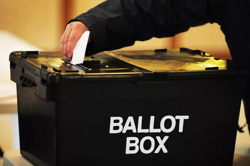 A voter placing a ballot paper in the ballot box at a polling station