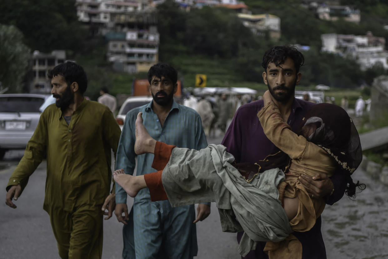 A man carries his sick daughter along a flooded road.