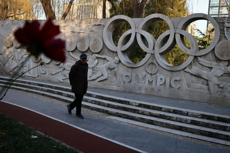 A man walks past a base relief containing the Olympic Rings as they city prepares for the Beijing 2022 Olympic Games in Beijing