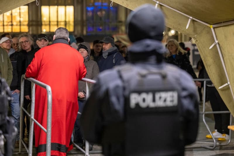 Police officers check people ahead of the end-of-year pontifical mass in Cologne Cathedral. Thomas Banneyer/dpa