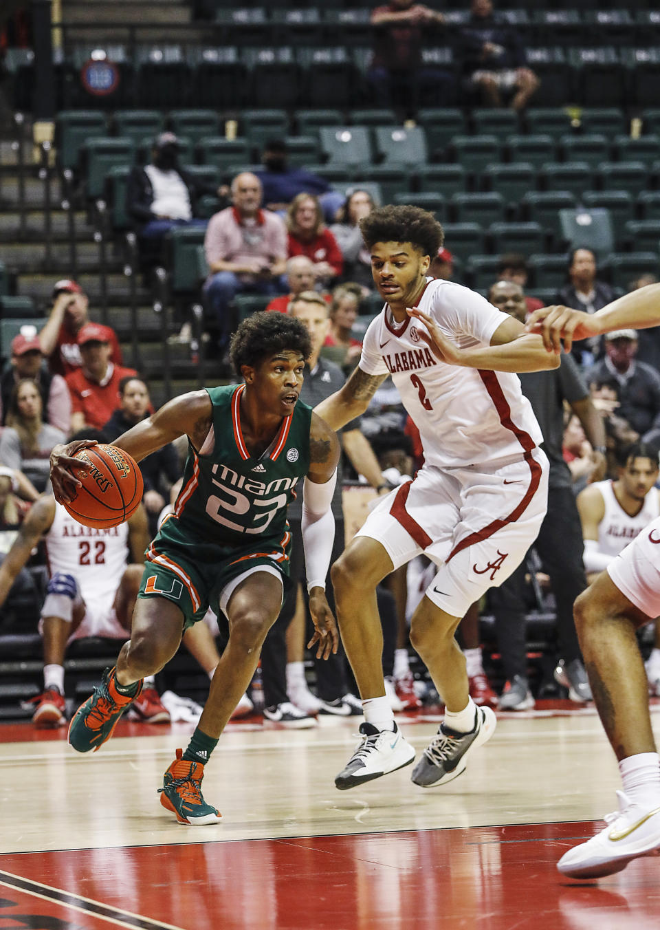 Miami guard Kameron McGusty drives to the basket in front of Alabama forward Darius Milesduring the first half of an NCAA college basketball game Sunday, Nov. 28, 2021, in Lake Buena Vista, Fla. (AP Photo/Jacob M. Langston)