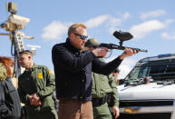 Acting Secretary of Defense Patrick Shanahan, center, fires a modified painted ball gun during a tour of the US-Mexico border at Santa Teresa Station in Sunland Park, N.M., Saturday, Feb. 23, 2019. Top defense officials toured sections of the U.S.-Mexico border Saturday to see how the military could reinforce efforts to block drug smuggling and other illegal activity, as the Pentagon weighs diverting billions of dollars for President Donald Trump's border wall. (AP Photo/Pablo Martinez Monsivais)