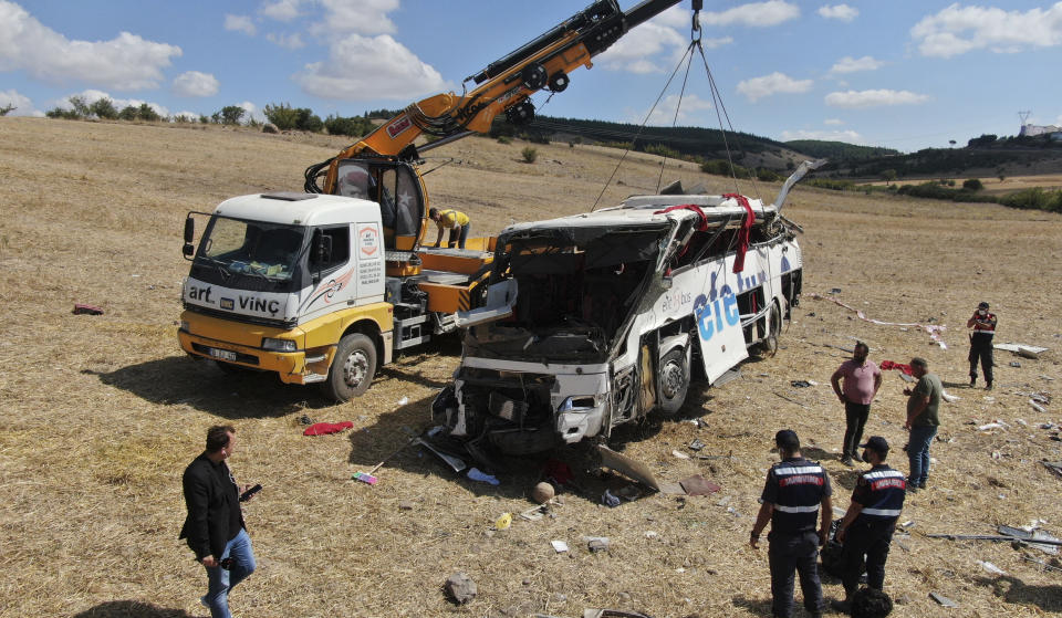 Officials investigate at the site of a bus crash, in Balikesir, western Turkey, Sunday, Aug. 8, 2021. A passenger bus has veered and tumbled off a highway in western Turkey, killing 14 people. The governor’s office of Balikesir province said said the bus overturned at 04:40 local time (0140 GMT) on Sunday. (IHA via AP)