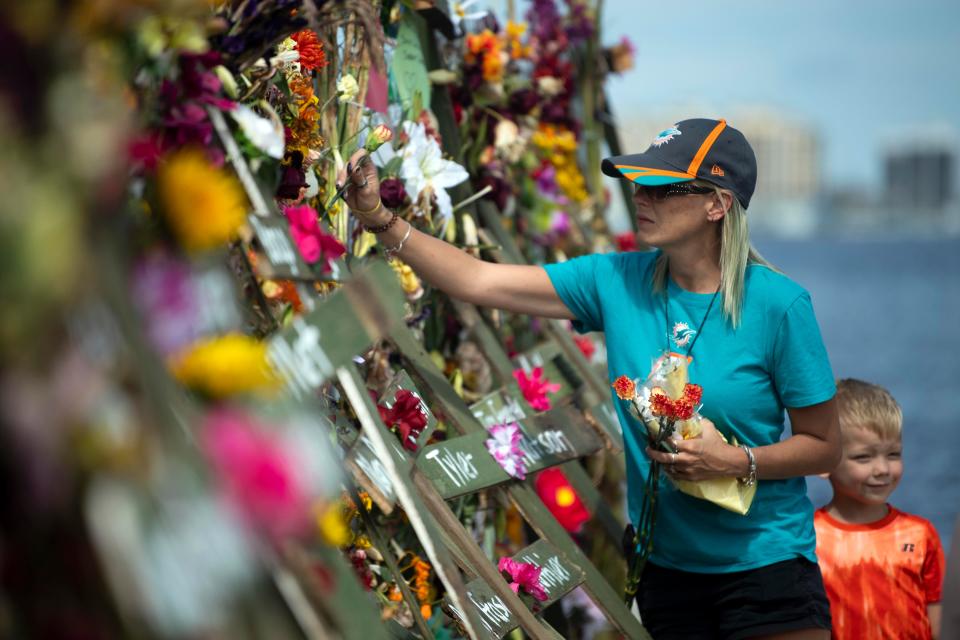 Cassaundra Arrington places flowers on the Hurricane Ian memorial at Centennial Park on Sunday, October 9, 2022 in Fort Myers, Fla. 