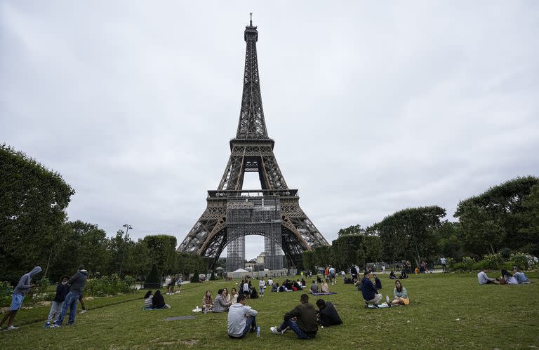 La gente se relaja en el jardín Champ-de-Mars junto a la Torre Eiffel en París