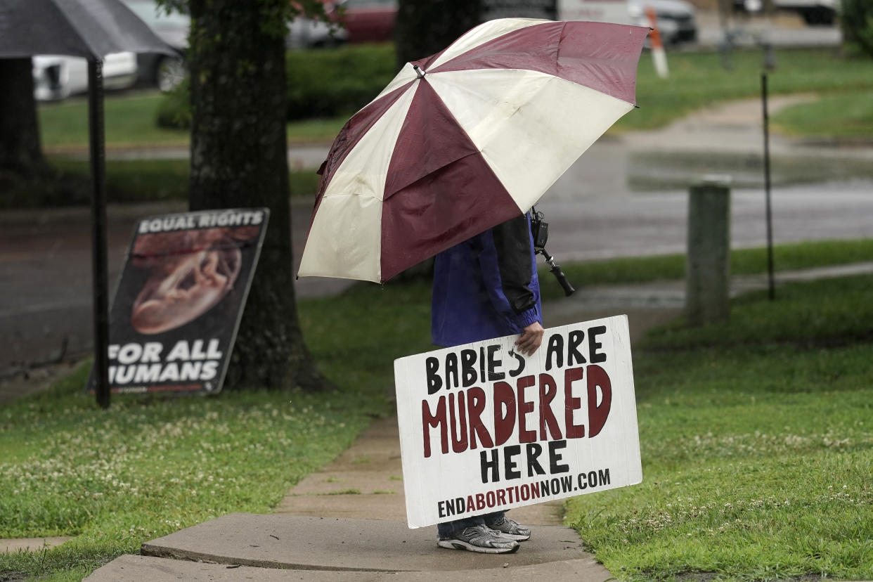 An anti-abortion advocate stands outside a Planned Parenthood clinic, holding a sign reading: Babies are murdered here.