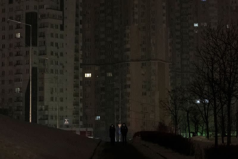 People walk in a dark park after critical civil infrastructure was hit by Russian missile attacks in Kyiv