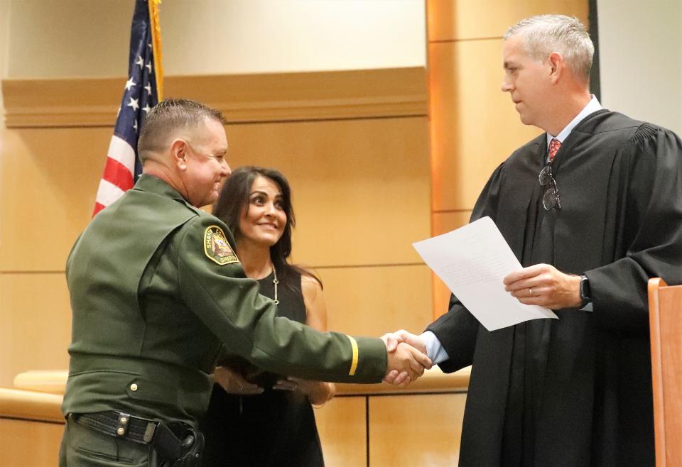 Shasta County Superior Court Judge Jody Burgess, right, shakes hands with new Shasta County Sheriff Michael Johnson after he was sworn in Friday, Aug. 13, 2021, in the Board of Supervisors chambers. Looking on is Johnson's wife, Rosemary.