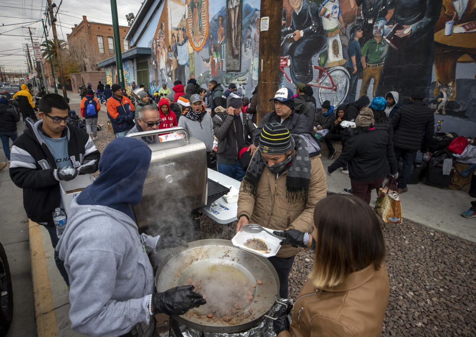 Migrants are served warm food donated by residents in downtown El Paso, Texas, Sunday, Dec. 18, 2022. Texas border cities were preparing Sunday for a surge of as many as 5,000 new migrants a day across the U.S.-Mexico border as pandemic-era immigration restrictions expire this week, setting in motion plans for providing emergency housing, food and other essentials. (AP Photo/Andres Leighton)