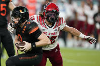 Miami quarterback Tyler Van Dyke (9) is sacked by North Carolina State linebacker Drake Thomas (32) during the first half of an NCAA college football game Saturday, Oct. 23, 2021, in Miami Gardens, Fla. (AP Photo/Wilfredo Lee)