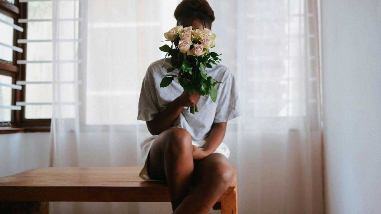 a man sitting at a table with flowers in his hand