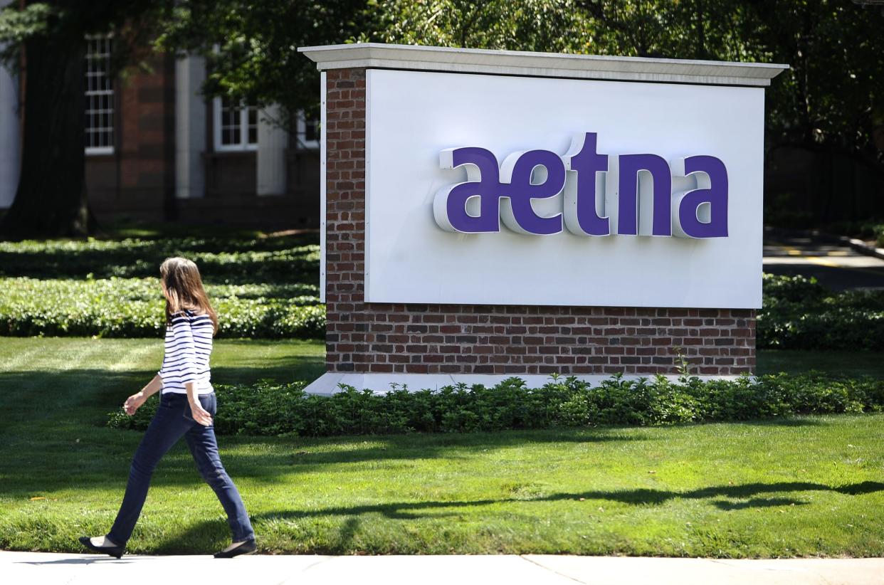 A pedestrian walks past a sign for health insurer Aetna Inc., at the company headquarters in Hartford, Conn.
