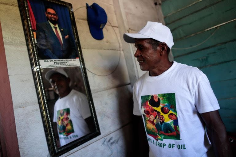 Un residente del poblado de Arau, en la región de Esequibo, posa junto al retrato del presidente Irfaan Ali