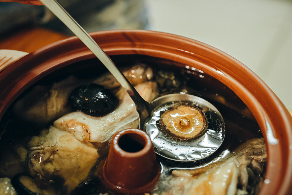 A pot of Yunnan-style steamed pot chicken was ready to eat. Scoop up a spoon of soup with a mushroom.