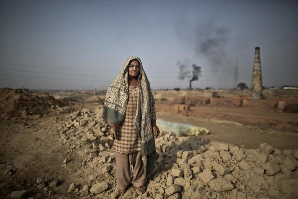 In this Wednesday, March 5, 2014, photo, Emna Mohammed, 65, a Pakistani brick factory worker, poses for a picture at the site of her work in Mandra, near Rawalpindi, Pakistan. Emna inherited her late husband's debt to the employer the amount of 95,000 rupees (approximately $950). (AP Photo/Muhammed Muheisen)