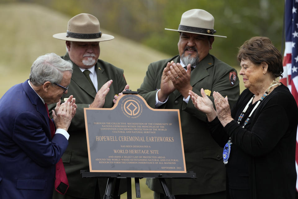 From left, Ohio Gov. Mike DeWine; Chris Alford, superintendent of Hopewell Culture National Historical Park; National Park Service Director Chuck Sams and Chief Glenna Wallace, of the Eastern Shawnee Tribe of Oklahoma, applaud after unveiling a replica of a plaque during the Hopewell Ceremonial Earthworks UNESCO World Heritage Inscription Commemoration ceremony, at the Mound City Group at Hopewell Culture National Historical Park in Chillicothe, Ohio, Saturday, Oct. 14, 2023. A network of ancient American Indian ceremonial and burial mounds in Ohio noted for their good condition, distinct style and cultural significance, including Hopewell, was added to the list of UNESCO World Heritage sites. (AP Photo/Carolyn Kaster)