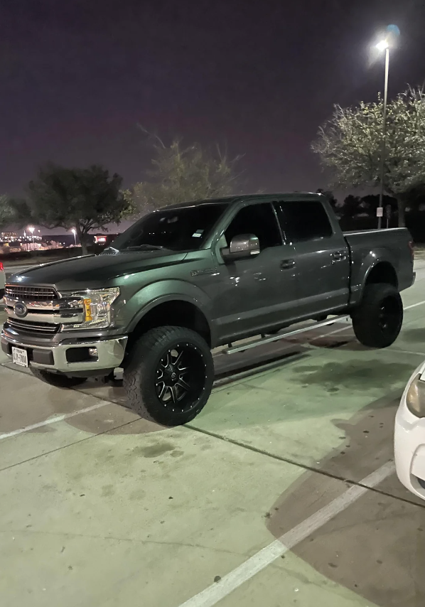 A lifted pickup truck parked in a lot at night. There are no people in the image