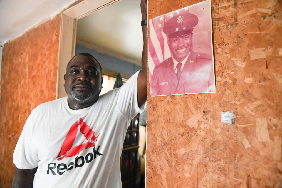 With tears in his eyes, Henry Thomas stands next to a photo of him when he was in the Air Force at age 18 inside his grandmother's house, where he was born and raised, in Walterboro, S.C., on Saturday, July 1, 2023.