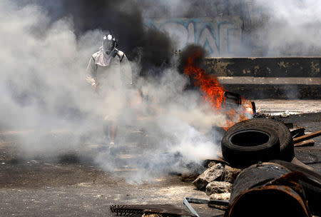 A demonstrator walks near a fire barricade at a rally against Venezuela's President Nicolas Maduro's government in Caracas, Venezuela, April 10, 2017. REUTERS/Carlos Garcia Rawlins