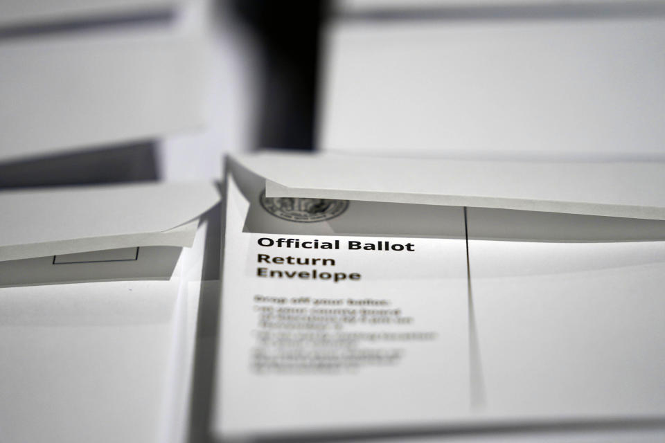 FILE - In this Thursday, Sept. 3, 2020, file photo, stacks of ballot envelopes waiting to be mailed are seen at the Wake County Board of Elections in Raleigh, N.C. A federal judge has blocked updated North Carolina absentee voting rules that gave voters more leeway to fix witness problems and extended the period when elections boards could accept mailed-in ballots. U.S. District Judge James Dever issued a temporary retraining order on Saturday, Oct. 3 that blocked the updated rules that resulted from a legal settlement with voting rights advocates. (AP Photo/Gerry Broome, File)