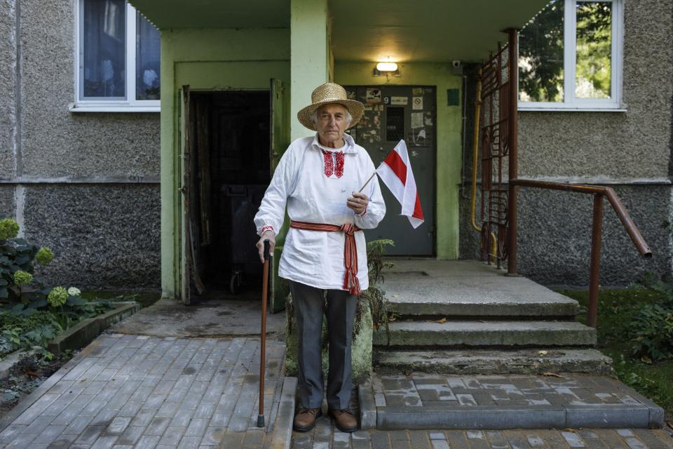 Yan Gryb, 85, poses for a photo holding a small Belarusian national flag at an entrance of his apartment building in Minsk, Belarus, Thursday, Sept. 10, 2020. The 85-year-old Hryb, who worked as a school teacher, said he hopes to live to the day when Lukashenko steps down, adding that it should be declared a national holiday. Hryb lamented that the Belarusians have been patient with Lukashenko for too long. (AP Photo)
