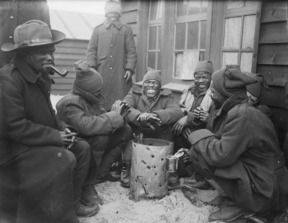 In this undated handout photo provided by the Imperial War Museum on Friday, Nov, 30 2018, African men gather around a fire for warmth during World War 1. Amid the fanfare marking the 100th anniversary of the end of World War I, little has been said about some crucial participants in the conflict: Africans. More than 1 million African soldiers, laborers and porters were vital actors in the war in Europe and especially in battles on the African continent, yet little commemorates their role. (Imperial War Museum via AP)